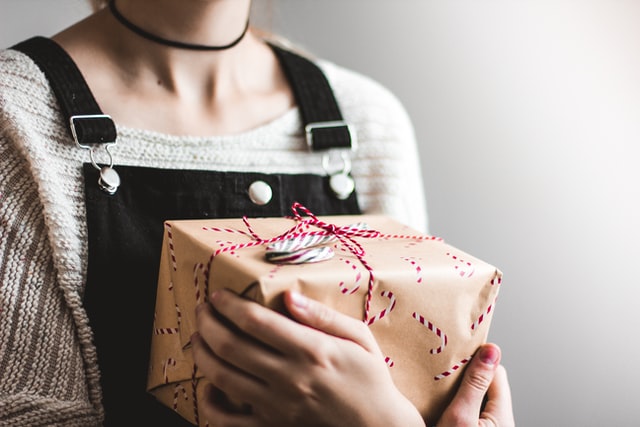 Person holding present topped with candy cane close to chest